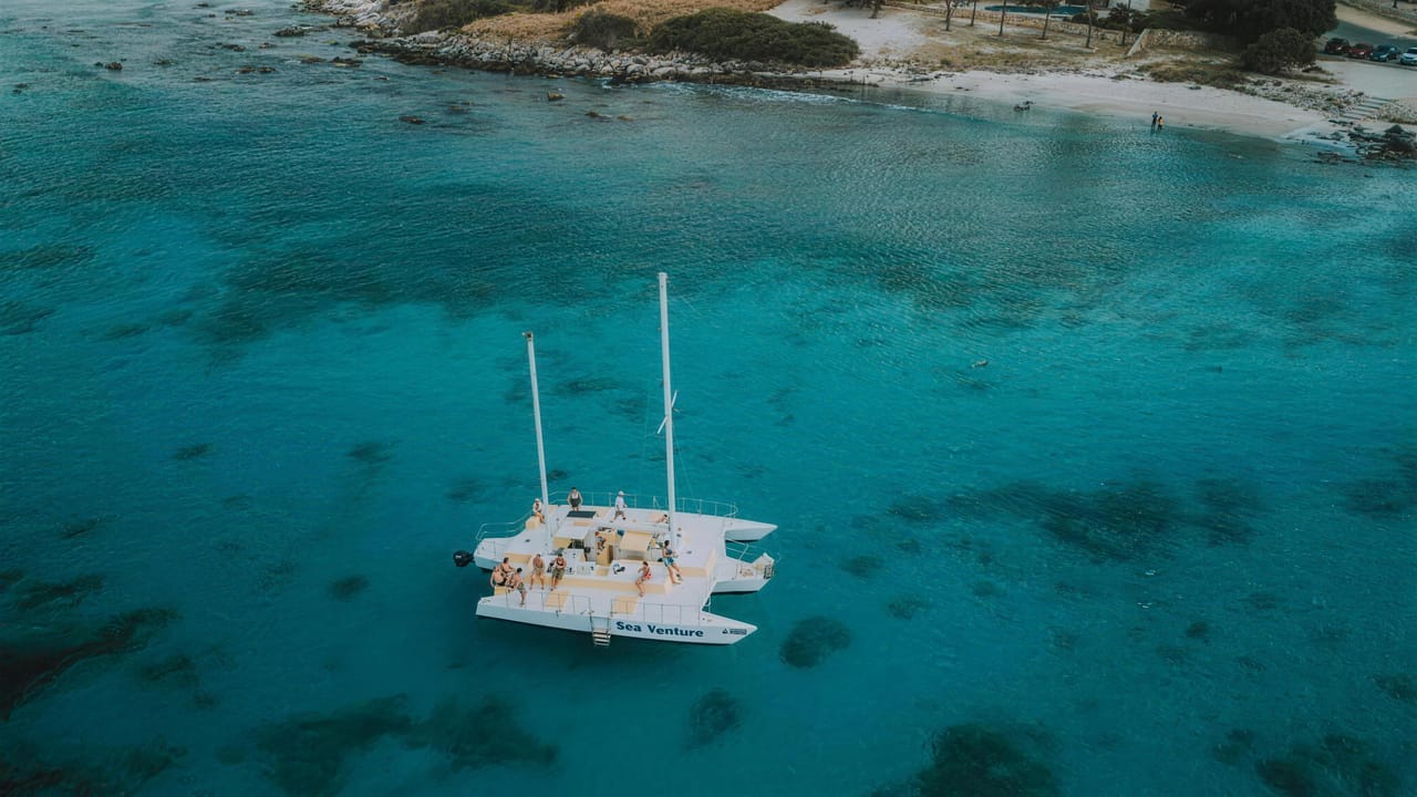 Drone view of the Sea Venture at anchor over the reef, with guests on deck