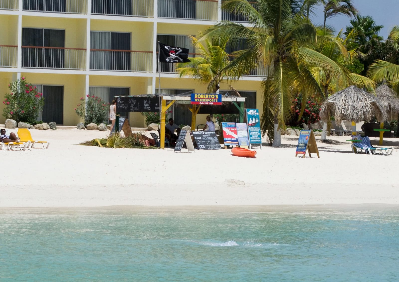 Roberto's Watersports tent on the beach, with price boards and the Holiday Inn behind it